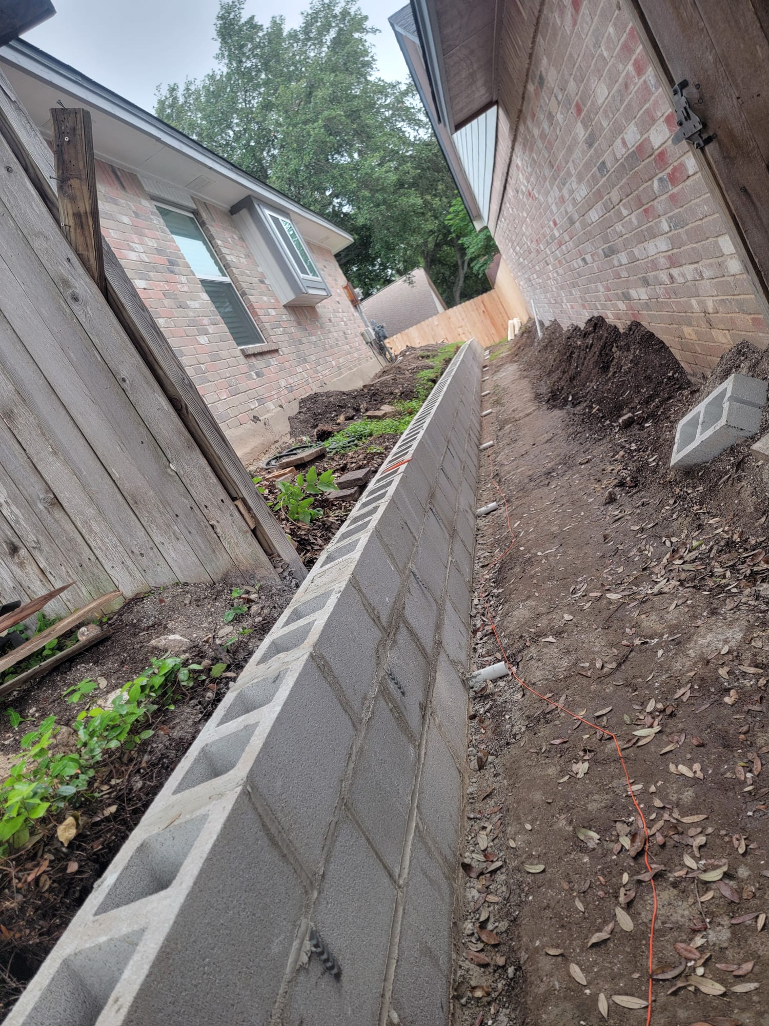 Concrete block retaining wall under construction between two brick homes