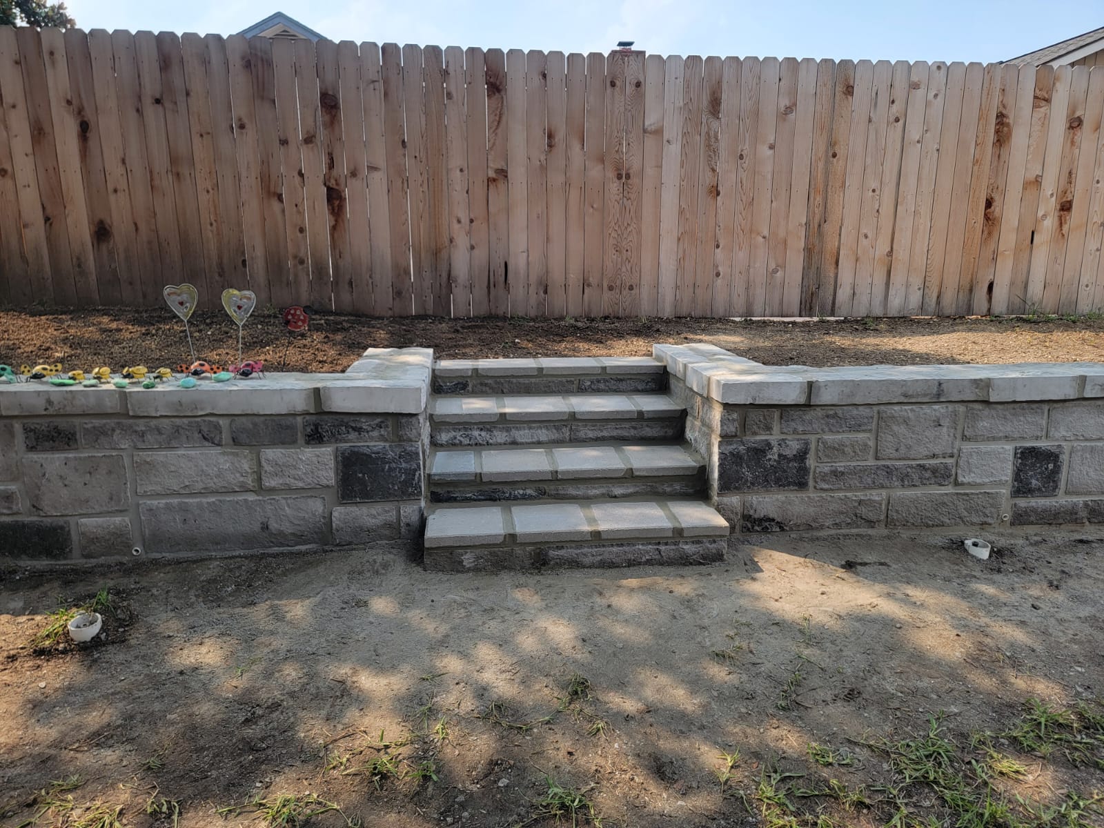 Retaining wall with central stone steps leading to an upper yard