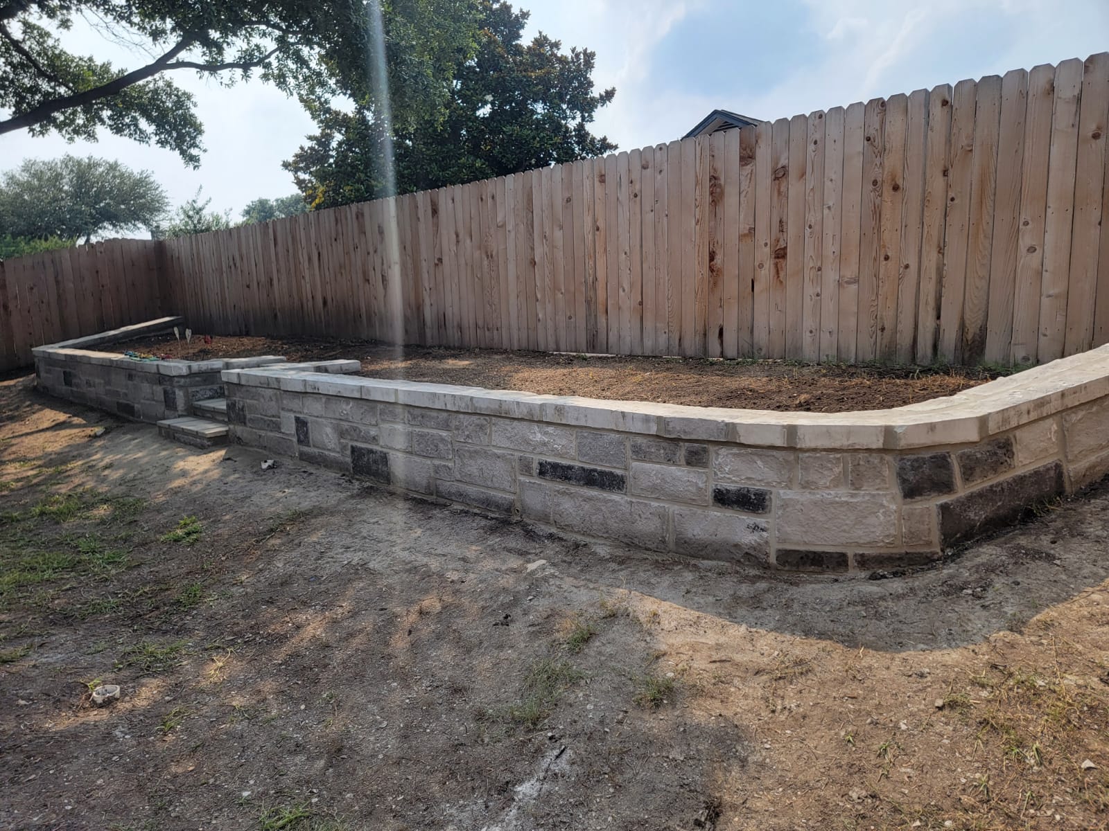 Low retaining wall with stone cap and built-in planting area