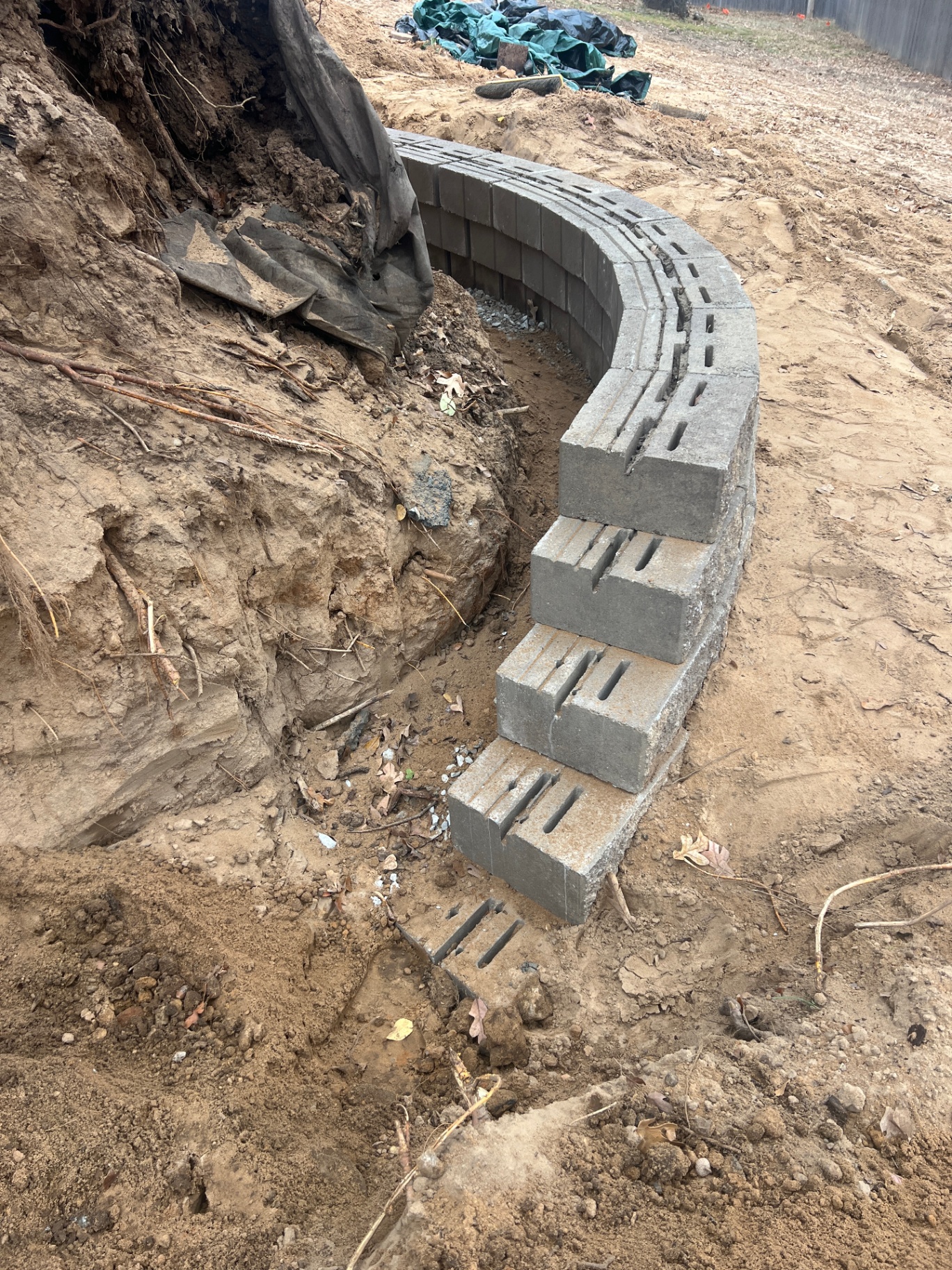 Curved segmental retaining wall being built on an excavated slope