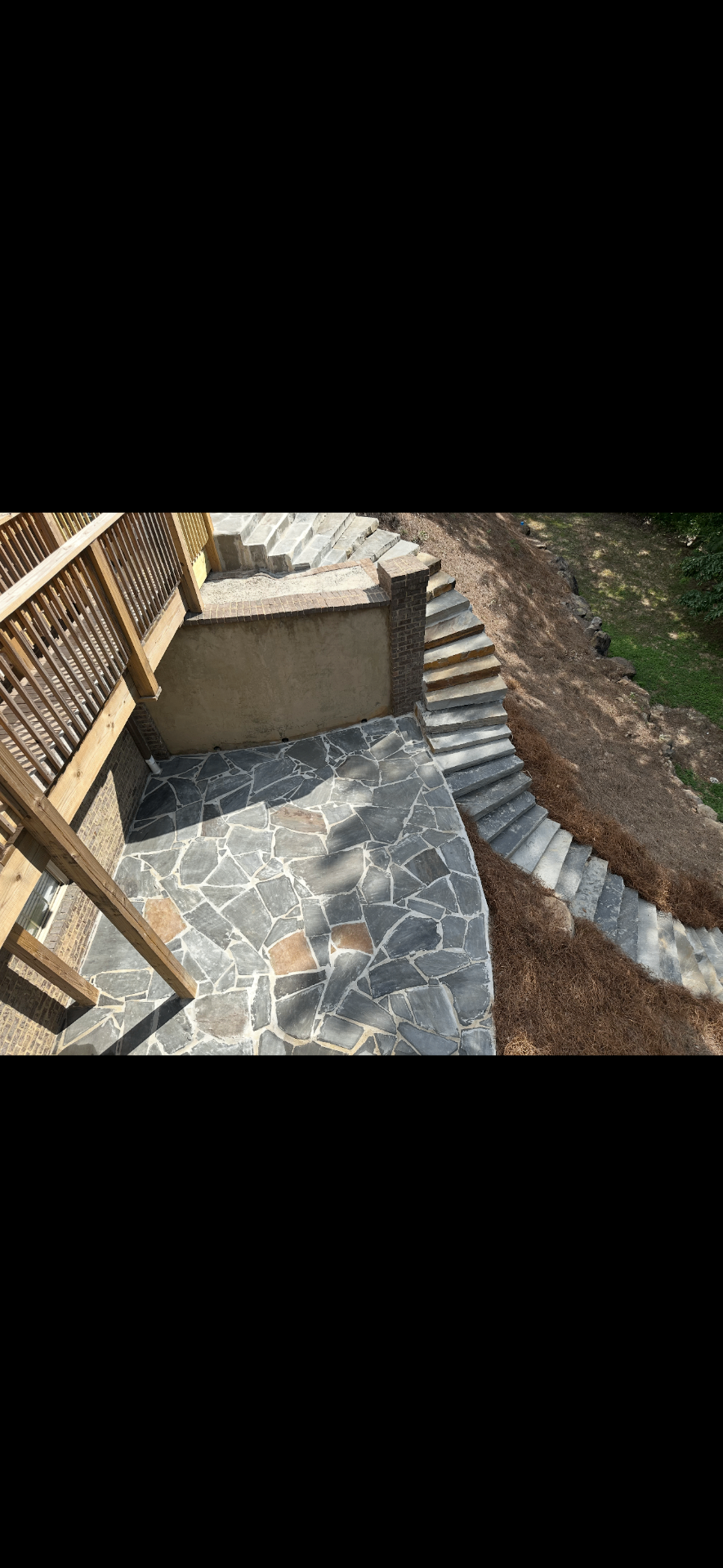 Flagstone patio and stone stair project beneath a deck